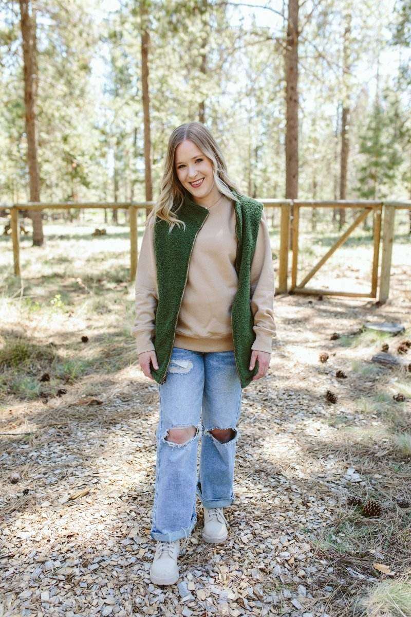 ADULT SHERPA/CORDUROY REVERSIBLE VEST in spruce green, worn open to show its soft sherpa lining and sleeveless design
