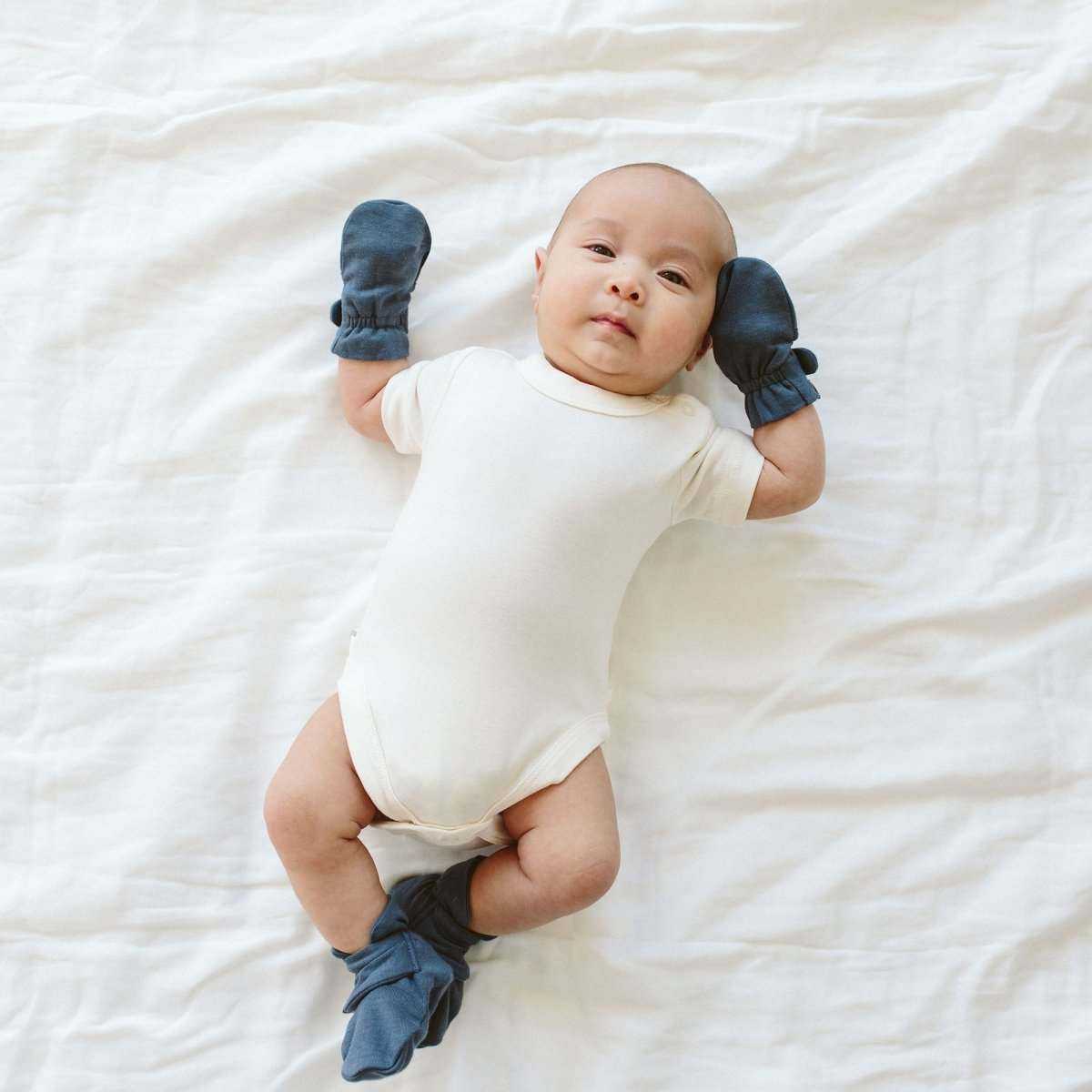 BABY MITTENS in midnight blue fabric with elastic cuffs, shown on an infant’s hands to prevent scratching