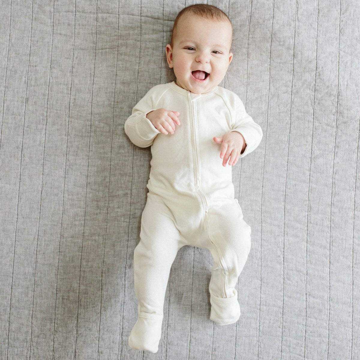 GROW WITH YOU FOOTIE in soft cloud-white fabric, featuring a two-way front zip and convertible covered feet