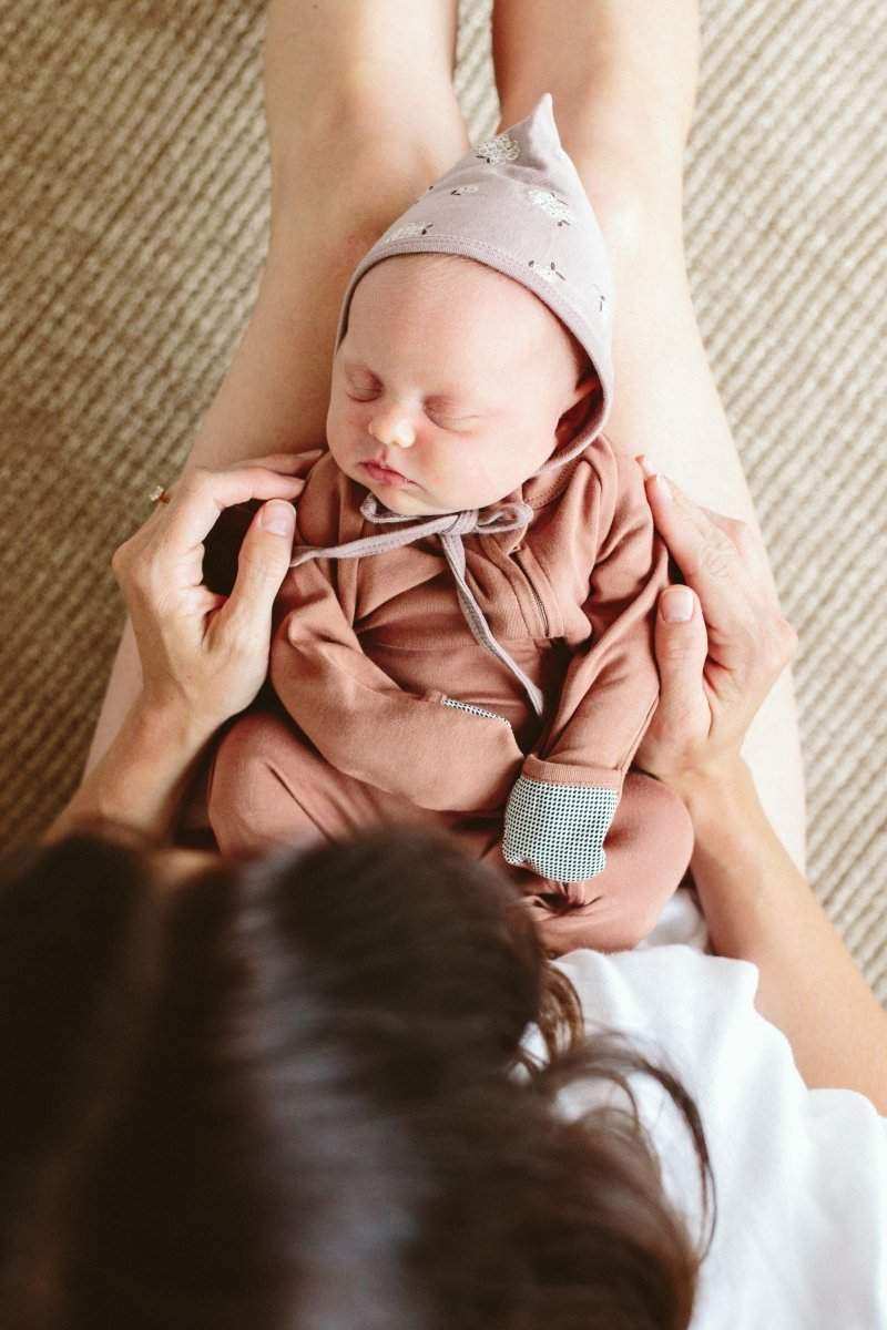 GROW WITH YOU FOOTIE in dusty rose, with long sleeves and a soft knit texture, shown on a newborn baby