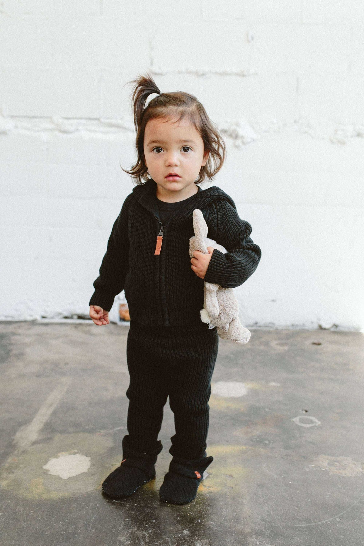 KNIT HOODIE in dark charcoal chunky ribbed knit, with a front zipper and oversized hood, worn with matching pants