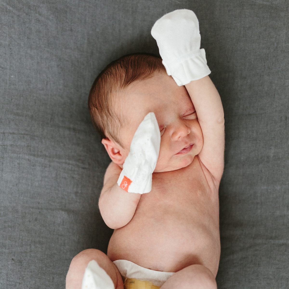 Preemie Sleep Set featuring a newborn wearing white stay-on mitts, with bare torso and a white diaper