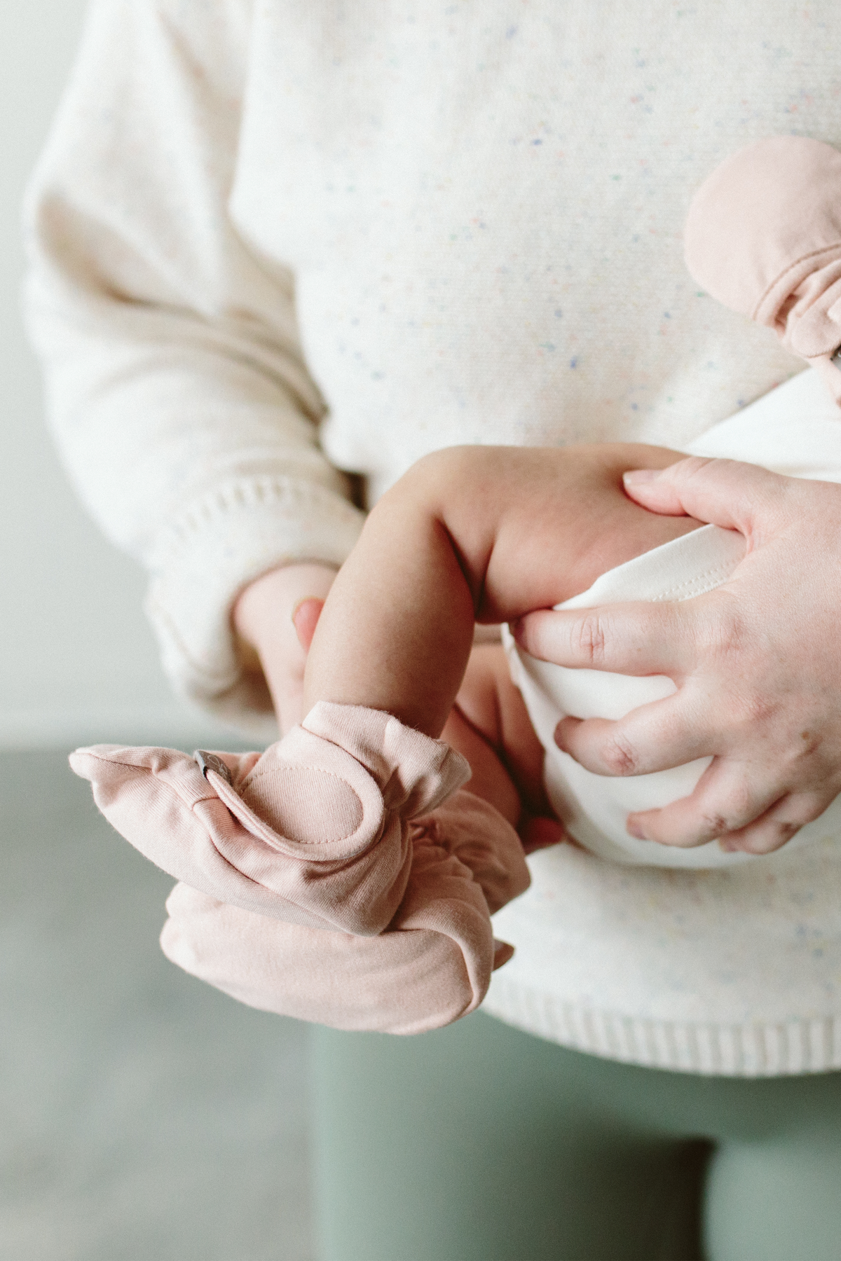 PREEMIE STAY ON BOOTS in dusty rose, soft fabric with an adjustable two-part closure wrapped around a tiny baby's foot