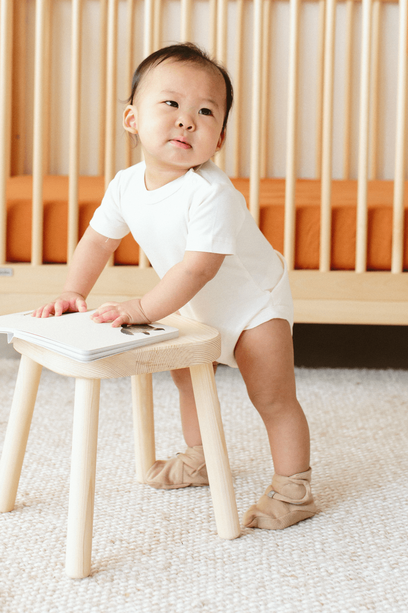 PREEMIE STAY ON BOOTS in sandstone beige, soft fabric with an adjustable wrap closure, worn by a baby