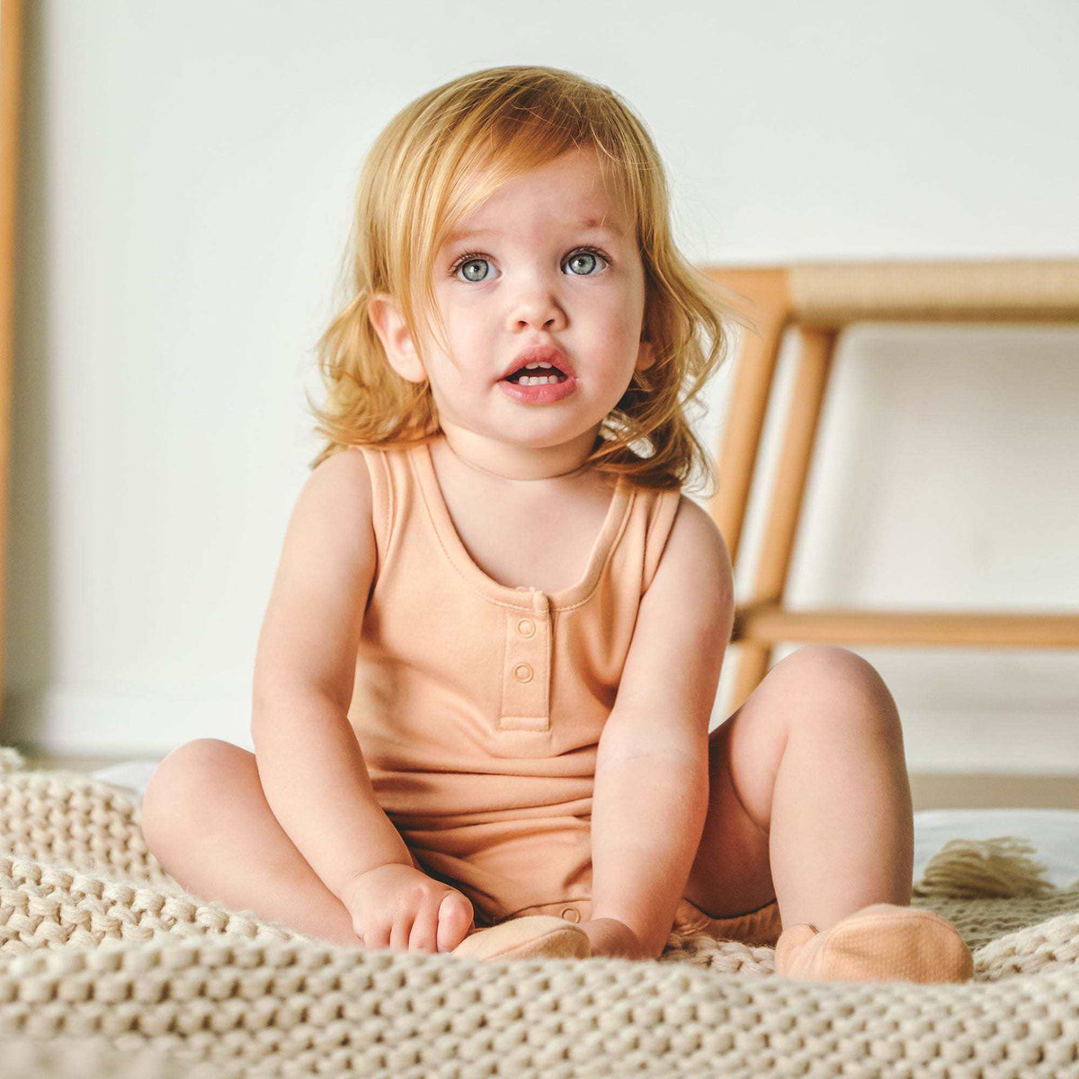 QUICK CHANGE ROMPER in peach with a soft sleeveless knit design, scoop neck, front buttons and bottom snaps