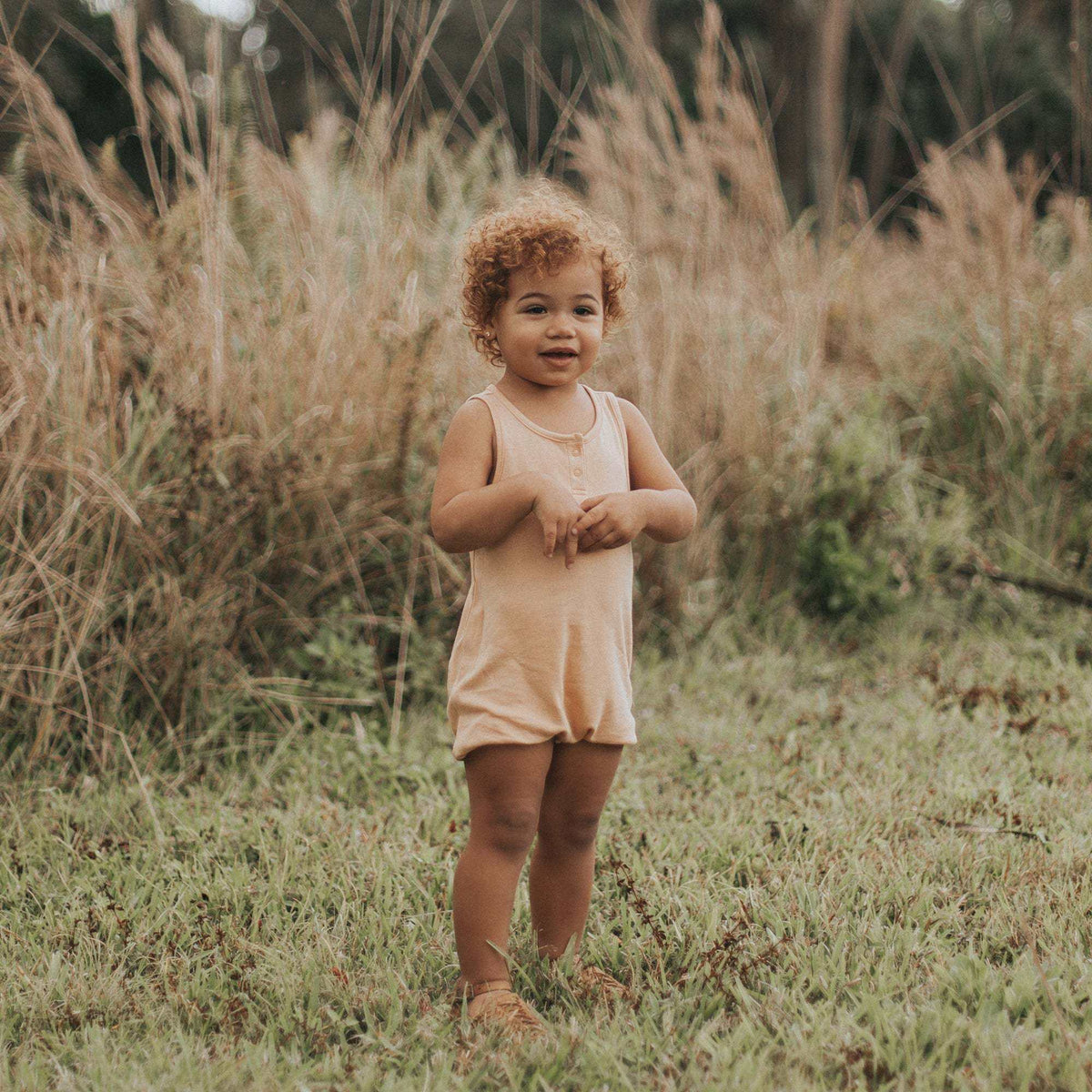 QUICK CHANGE ROMPER in soft peach with a solid sleeveless design, scoop neckline, and relaxed fit for warm-weather play