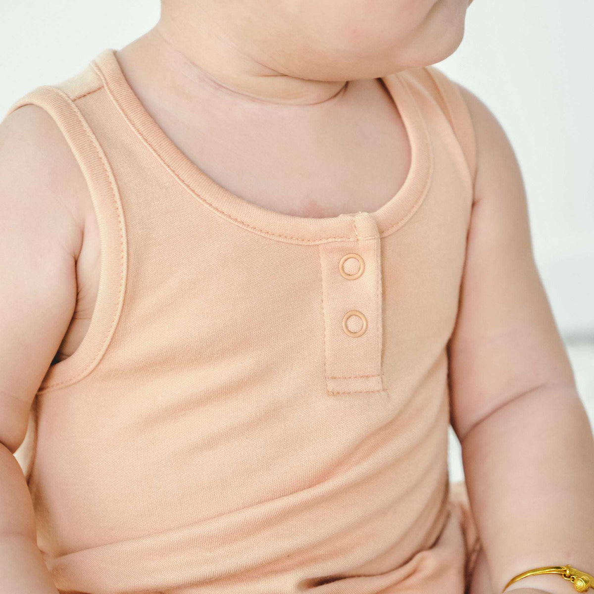 QUICK CHANGE ROMPER in a solid peach shade with a soft knit fabric, sleeveless cut, and two-button neckline