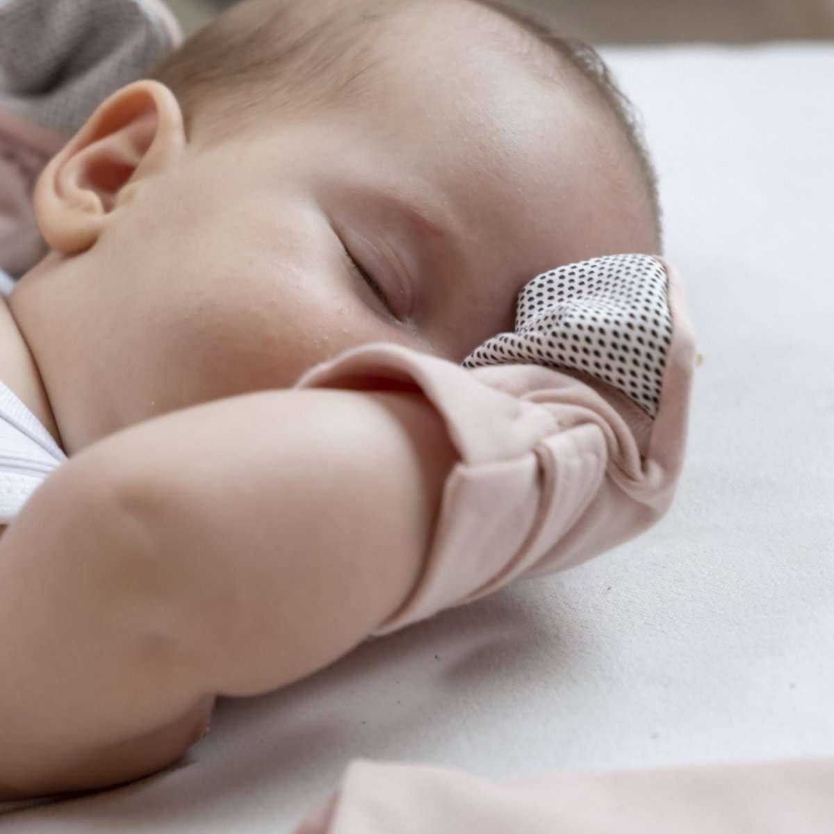 Quiet Night Starter Set rose baby mitt in soft pink fabric with a white and black dotted cuff, worn by a baby