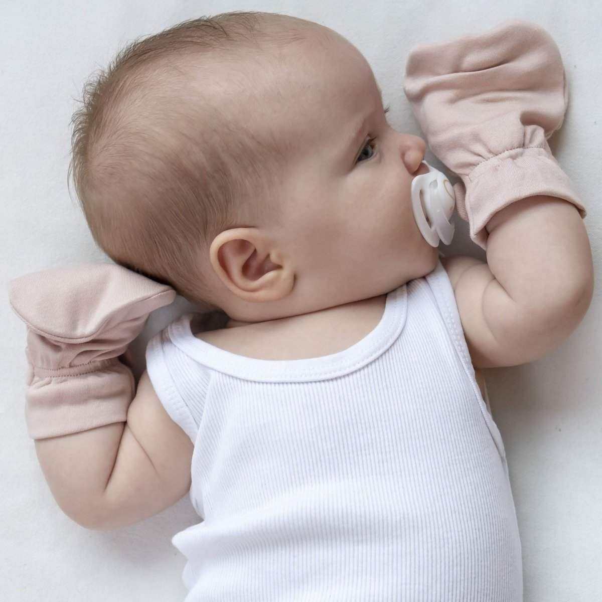 stay on 2-pack mitts in soft blush pink bamboo cotton, worn by a baby with folded cuffs