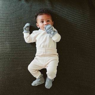 STAY ON 2-PACK MITTS baby wearing soft light gray mitts with ribbed cuffs and secure wrist closures