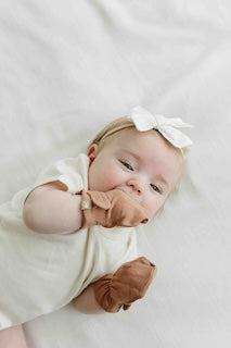 STAY ON 2-PACK MITTS in soft tan fabric, shown on a baby with a secure wrist closure