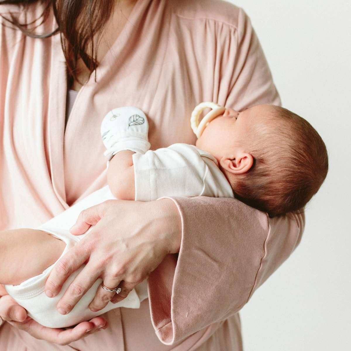 stay on 2-pack mitts in soft white fabric with a delicate gray abstract floral print on a baby's hand