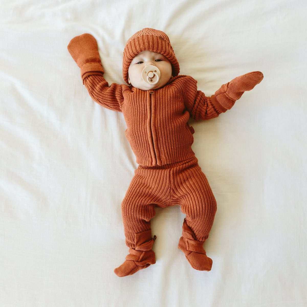 Stay on Knit Boots are burnt clay ribbed knit baby booties with soft fabric, ankle cuffs and adjustable wrap closures.