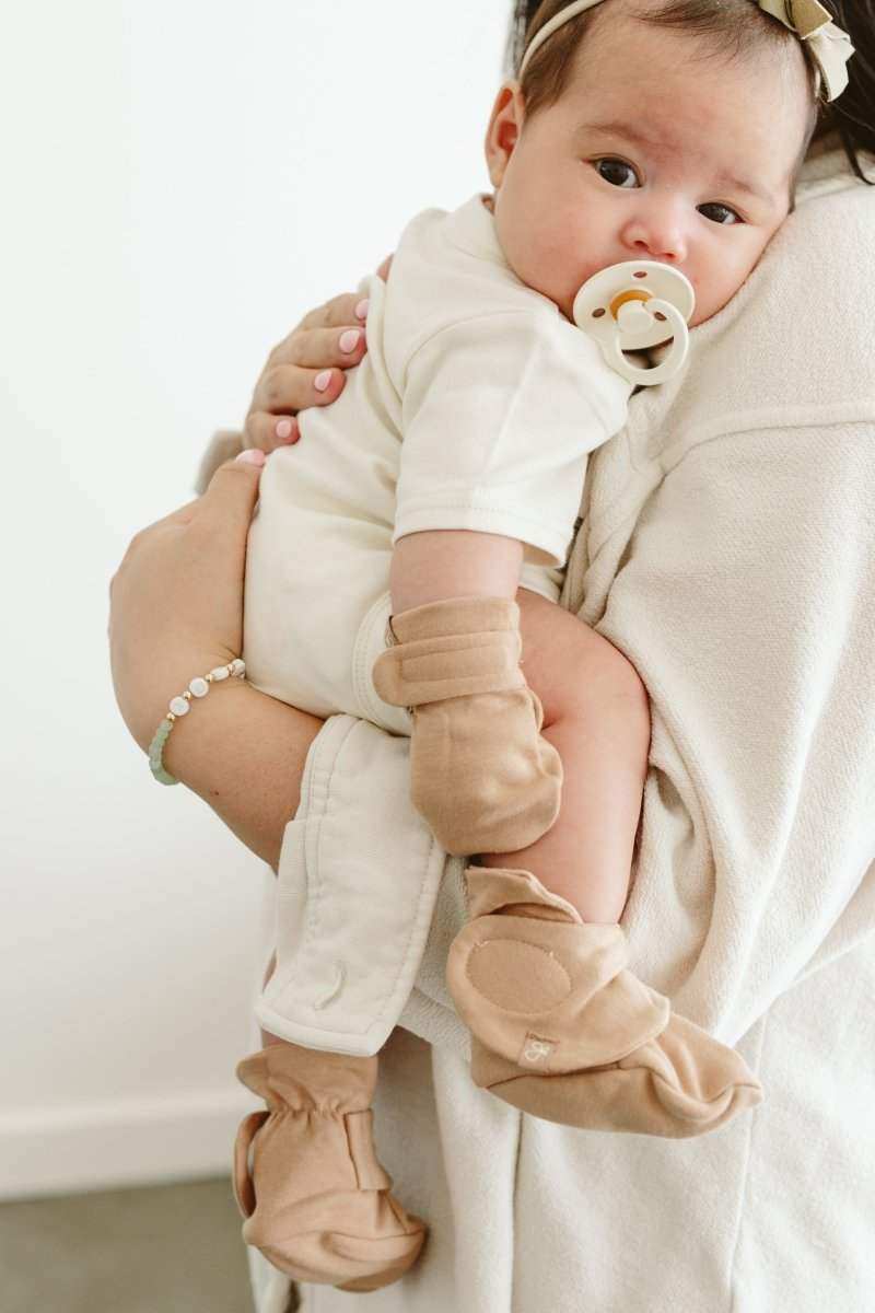 STAY ON MITTS in sandstone beige, soft fabric with adjustable wrist closures shown on a baby’s hands