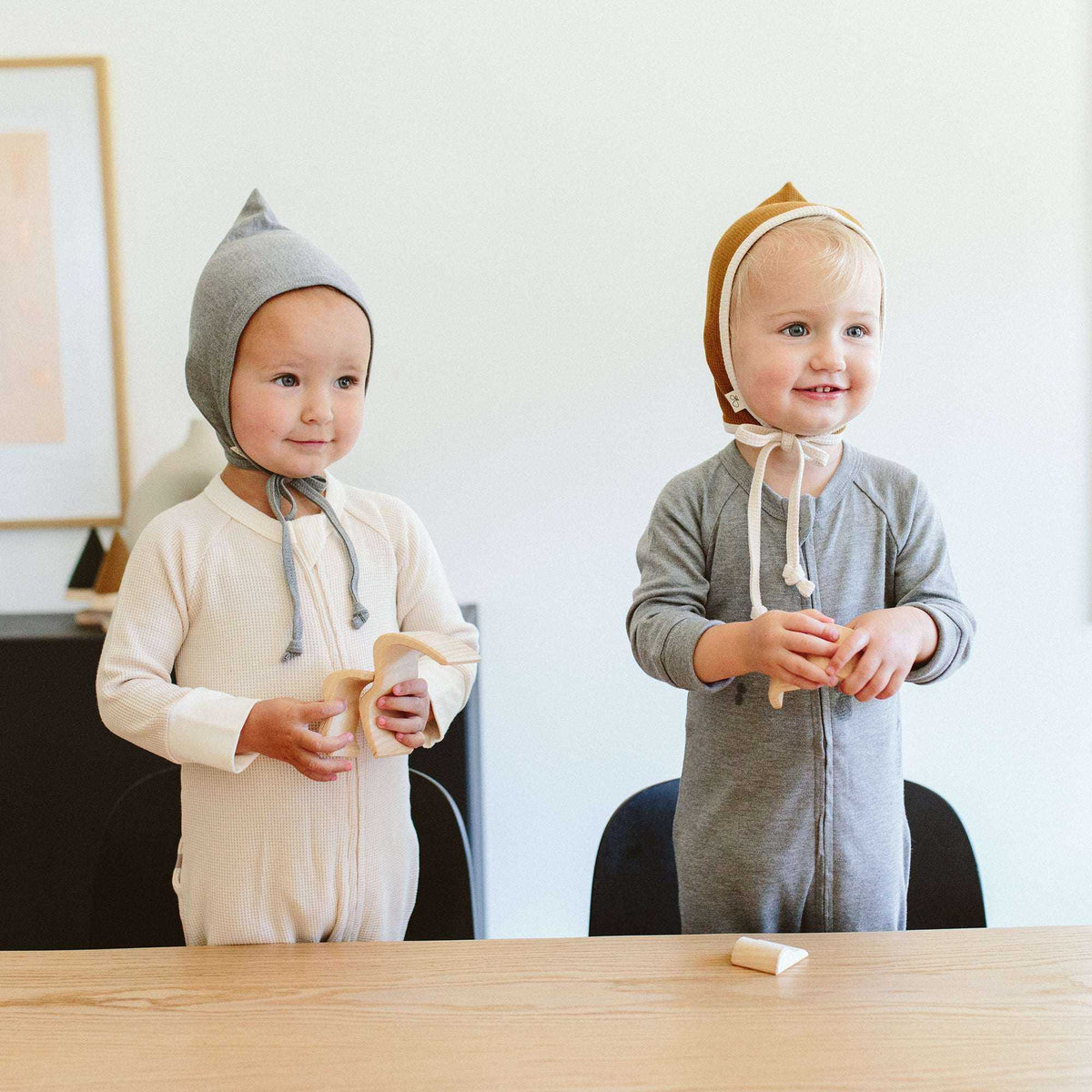 Welcome Home Set with two babies wearing cream and grey zip-front outfits, soft tied bonnets and matching accessories