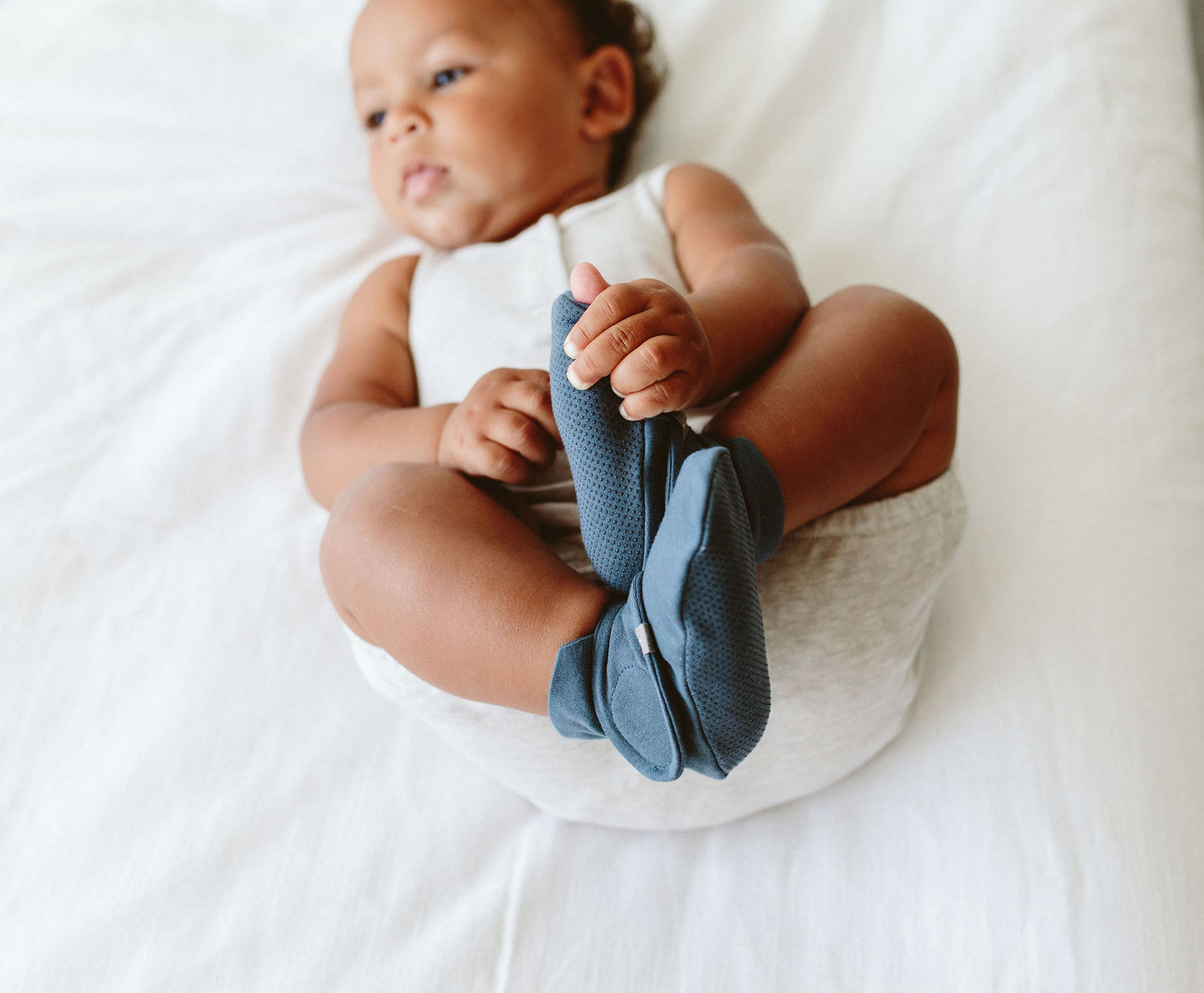 Welcome Home Set featuring a baby in a white bodysuit holding soft slate-blue footed babywear with fold-over cuffs