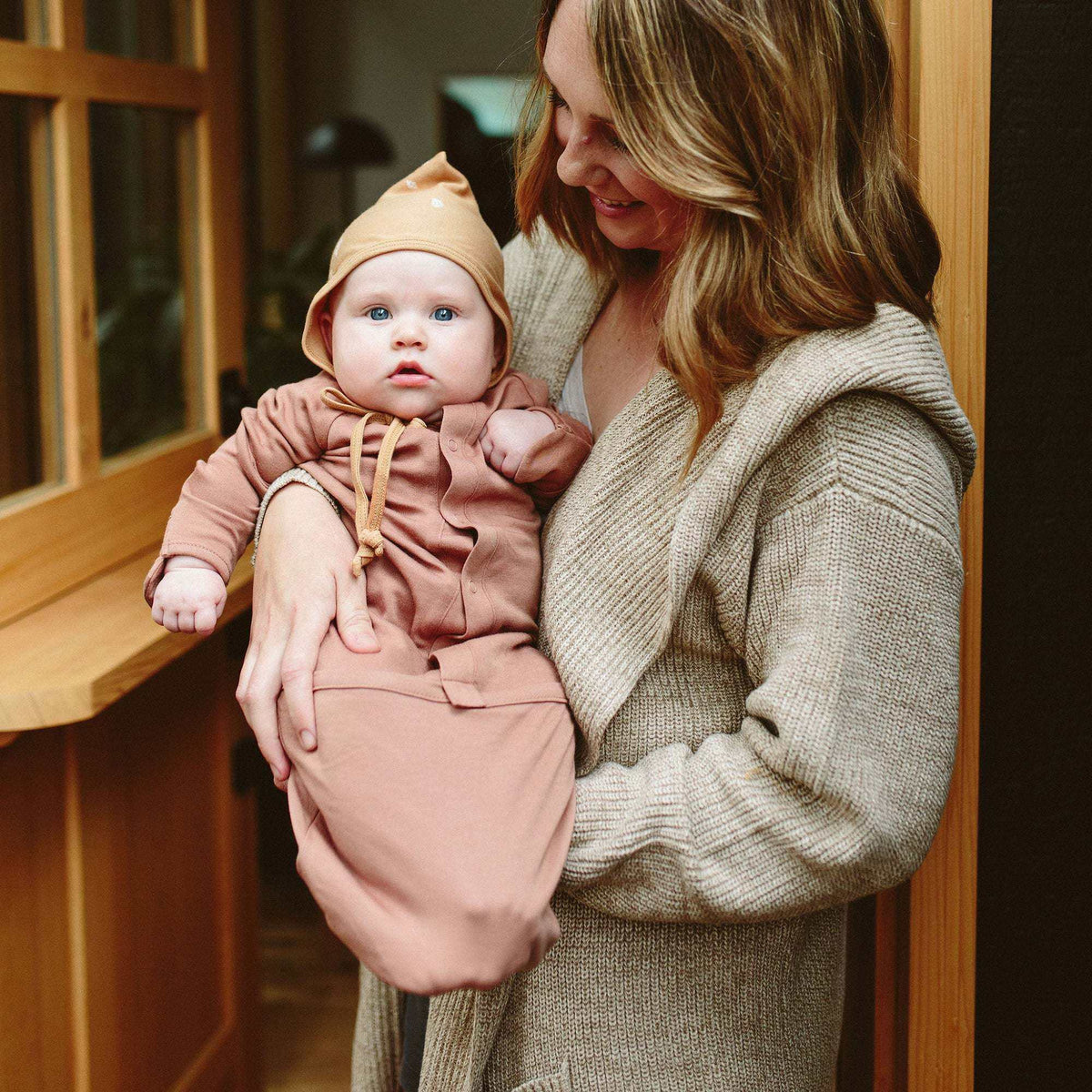 Welcome Home Set featuring a baby in a dusty rose convertible gown and matching peach knit hat with tie