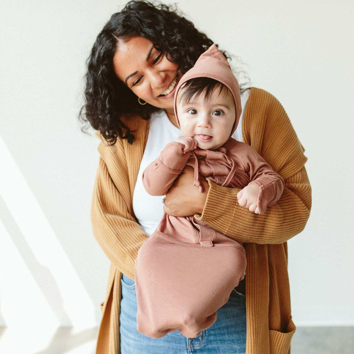 Welcome Home Set with baby wearing a dusty rose hooded convertible gown and matching mitts, held by an adult