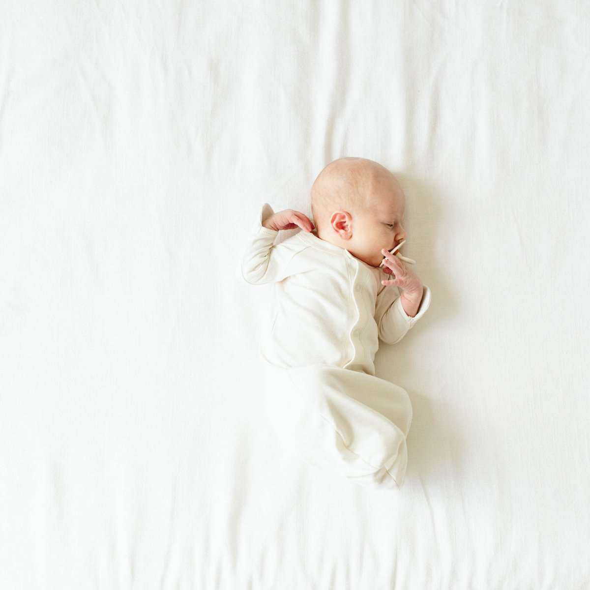 24 HOUR CONVERTIBLE GOWN in soft cloud cream fabric, shown on a baby with long gown-style coverage and covered hands