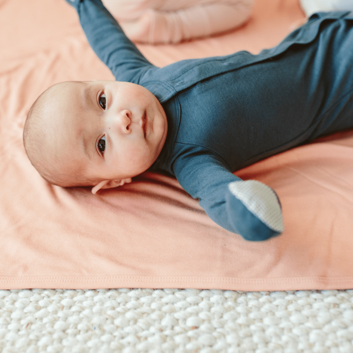 24 HOUR CONVERTIBLE GOWN in muted midnight blue, worn by a baby, with long sleeves and a built-in patterned mitt
