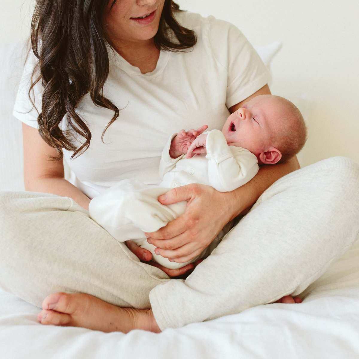 24 HOUR CONVERTIBLE GOWN in soft white bamboo cotton, worn by a newborn with long sleeves and covered hands