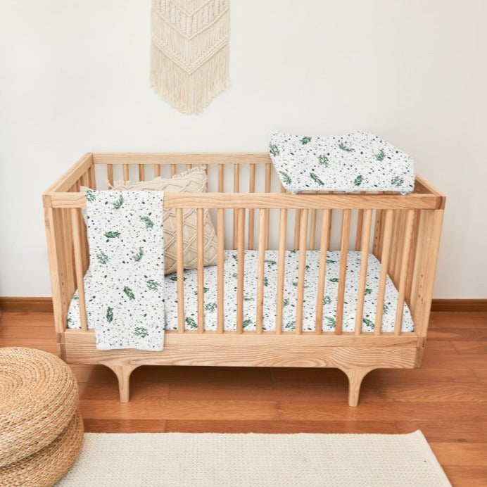 Modern nursery design with macrame wall hanging and matching organic cotton bedding set.