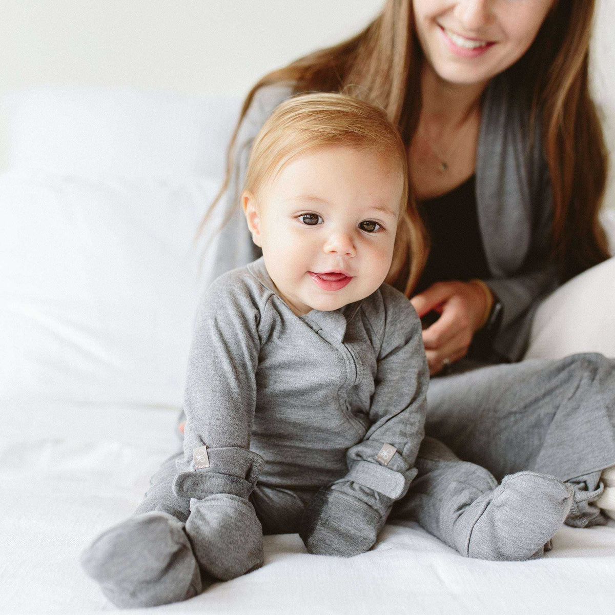 GROW WITH YOU FOOTIE in soft heather gray, featuring a wrap-style front, long sleeves, and fold-over foot cuffs