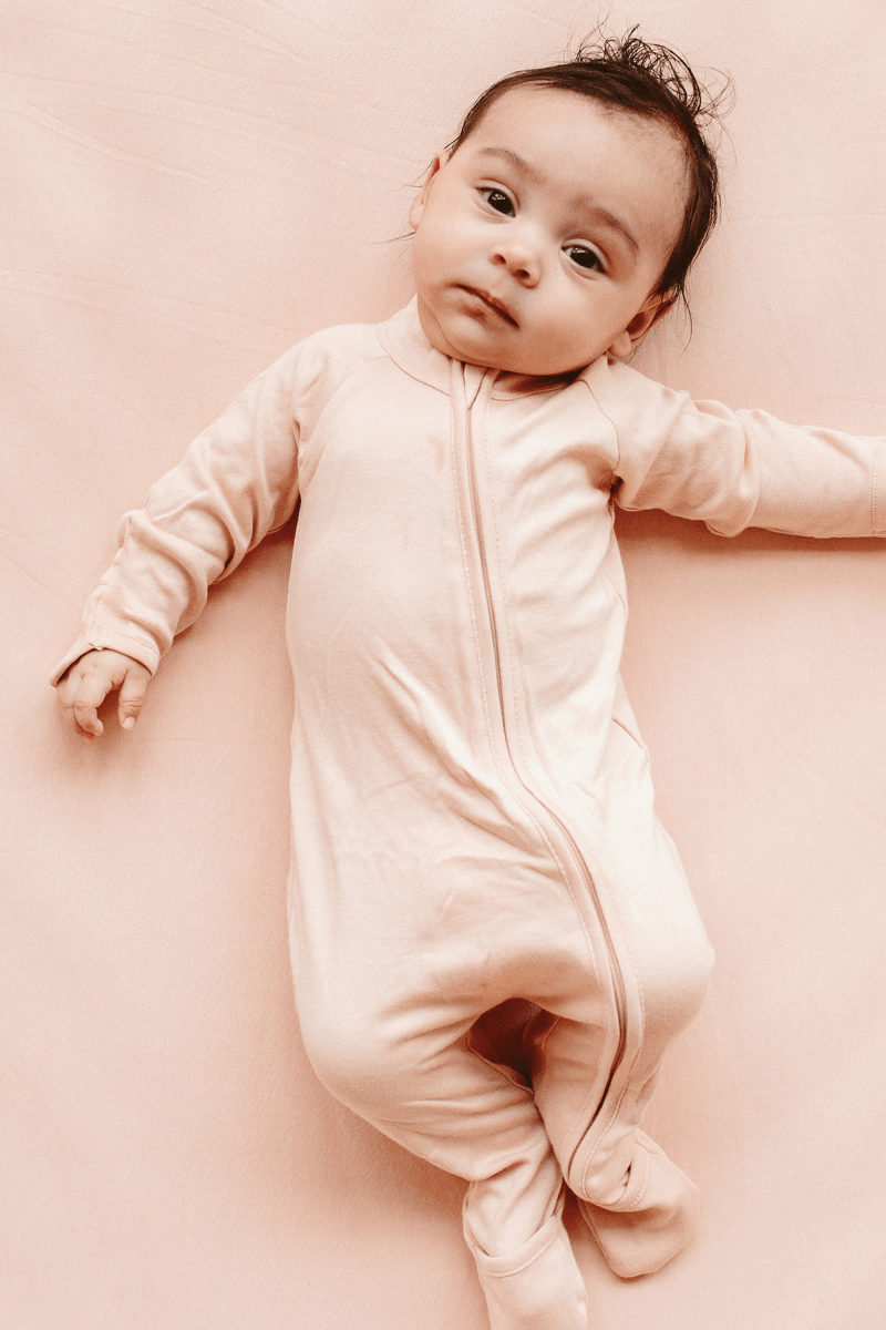 GROW WITH YOU FOOTIE in soft pale rose fabric with a solid colour, long sleeves, and a front two-way zipper