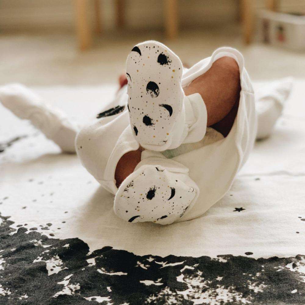 STAY ON 2-PACK BOOTS are soft white baby booties with adjustable closures and black moon and speckle prints