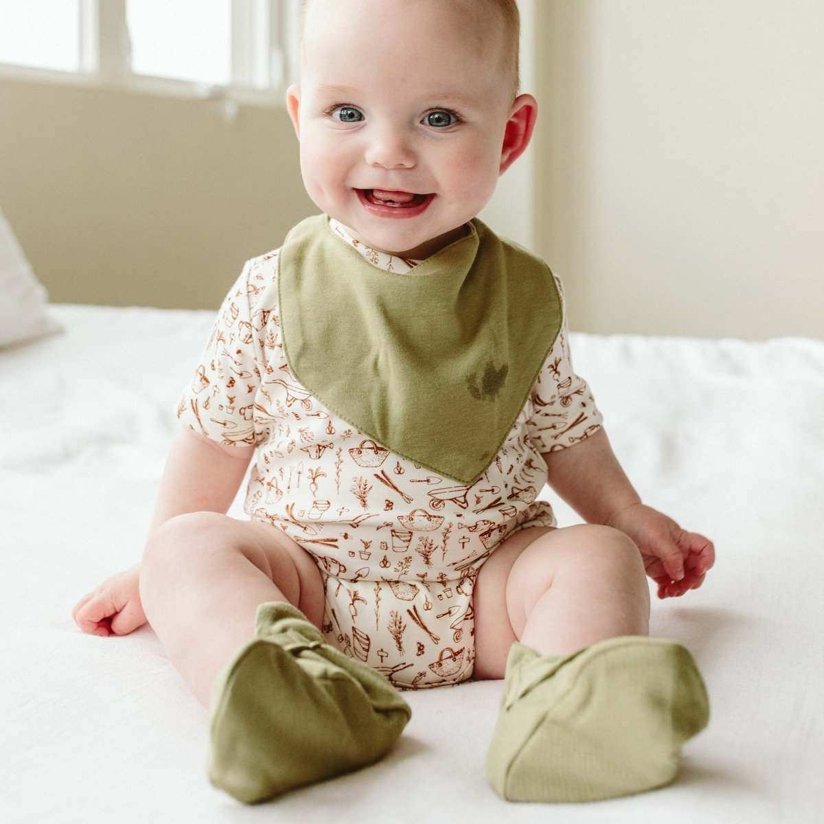 STAY ON BOOTS in sage green soft fabric, worn with a cream baby outfit patterned with delicate brown botanicals