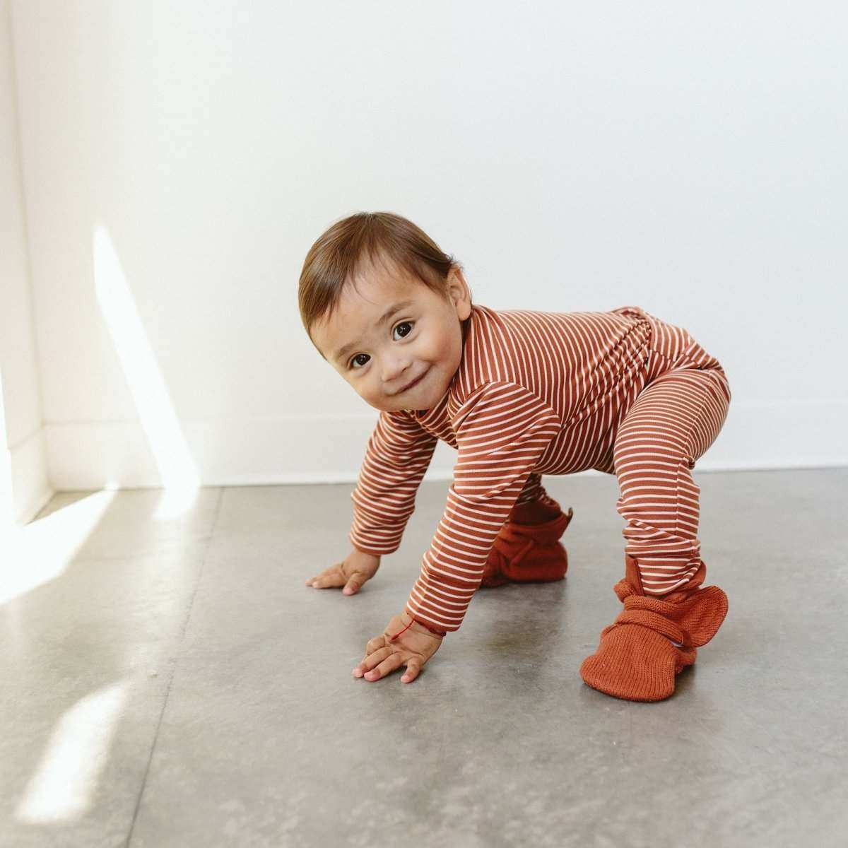 Stay on Knit Boots in clay red knit cotton, soft ankle-high baby booties with adjustable wraparound closures